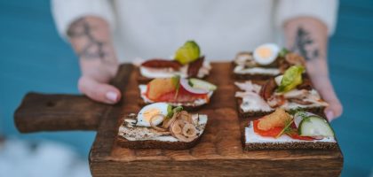 Delicious open-faced sandwiches with various toppings served on a wooden board, showcasing exquisite food styling.