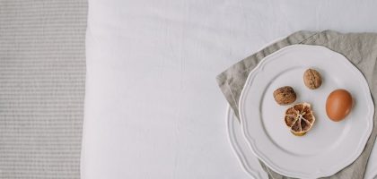 Artistic still life featuring egg, dried lemon, and walnuts on a white plate.