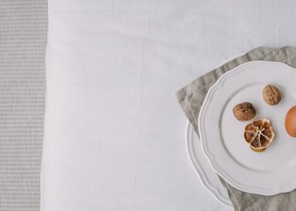 Artistic still life featuring egg, dried lemon, and walnuts on a white plate.